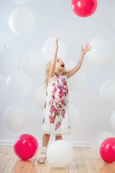 Bambina con palloncini bianchi e rossi al coperto — Foto Stock