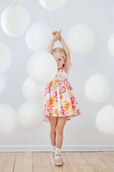 Klein meisje met witte ballonnen indoor — Stockfoto
