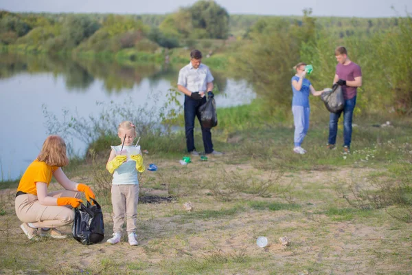 Family picks up trash on the beach in summer — Stock Photo, Image