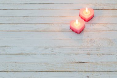 Beyaz ahşap arka planda pembe yanan mumlar