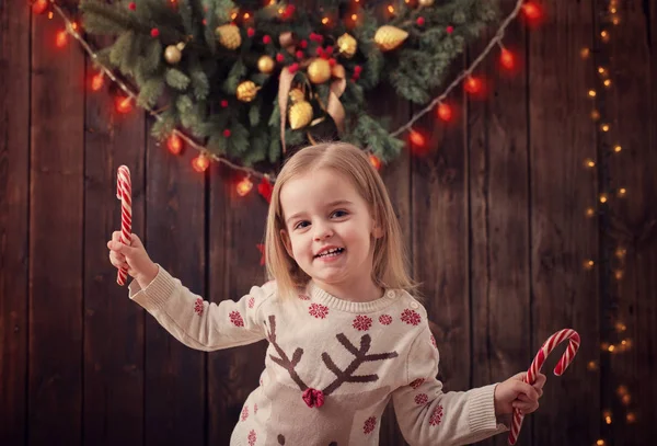 Klein meisje met kerstversiering op donkere houten achtergrond — Stockfoto