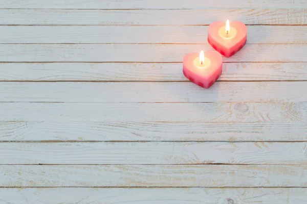 Розовые горящие свечи на белом деревянном фоне — стоковое фото