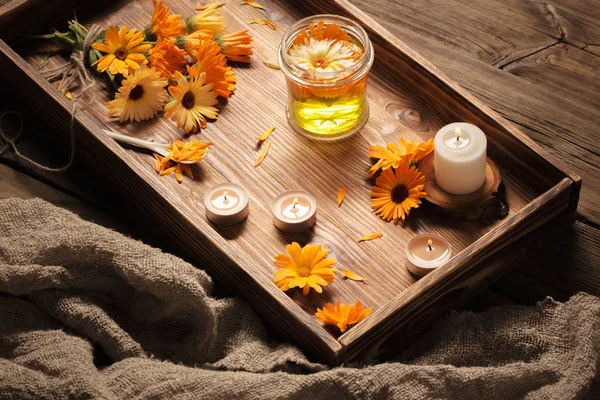 Medicinal flowers of calendula with burning candles  on dark woo — Stock Photo, Image