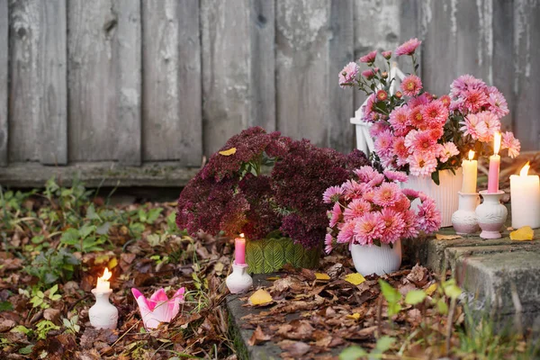 Chrysanthèmes avec des bougies allumées dans le jardin d'automne — Photo