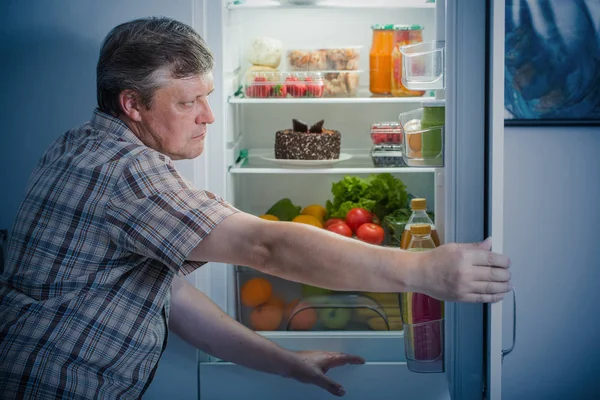 Displeased man looks  in the fridge at night — Stock Photo, Image