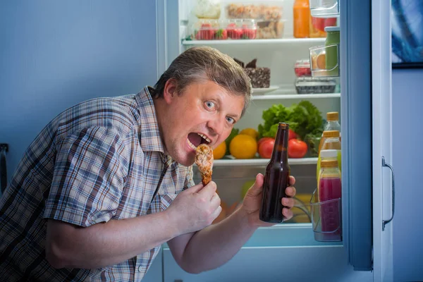Zralý muž v lednici s nohou piva a kuřecím masem — Stock fotografie