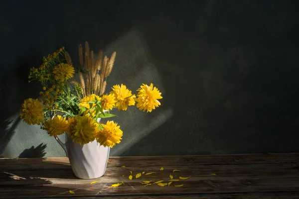 Yeliow flowers in white jug on dark background — Stock Photo, Image