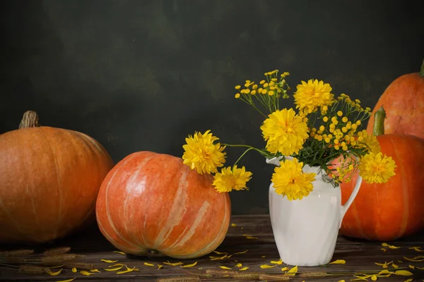 Eski ahşap masa üzerinde sarı çiçekler ve balkabaklarıyla durgun bir hayat — Stok fotoğraf