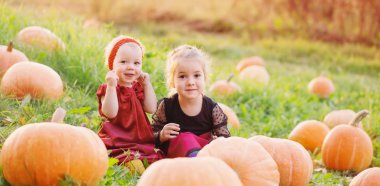 Gün batımında turuncu balkabaklı iki küçük kız