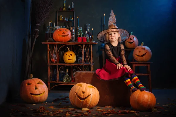 Kleine Hexe mit Halloween-Kürbissen drinnen — Stockfoto