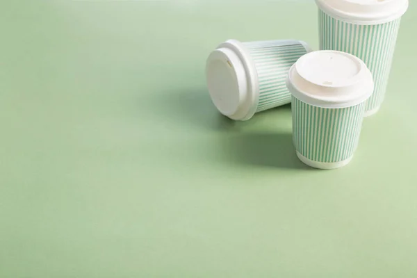 Wegwerp papier beker met koffie op groene achtergrond — Stockfoto