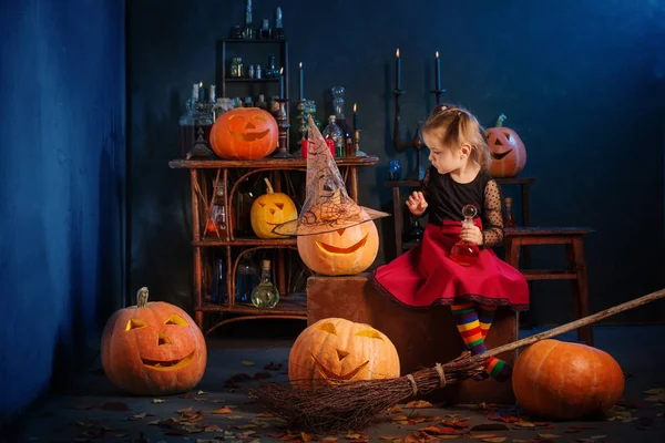 Kleine heks met Halloween pompoenen binnen — Stockfoto