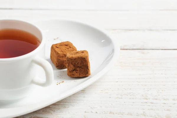 Tasse de thé avec bonbons au chocolat sur table en bois — Photo