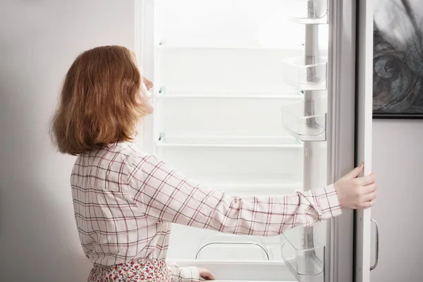 Девочка-подросток у пустого холодильника — стоковое фото