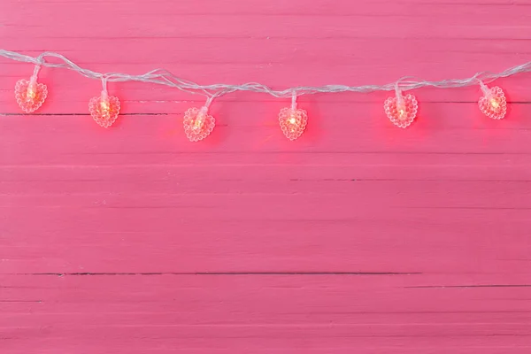 Guirnalda en forma de corazón sobre fondo de madera rosa — Foto de Stock