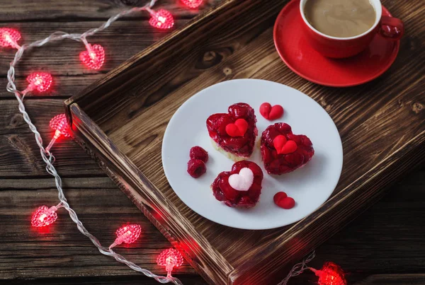 Пирожные в форме сердца и чашка кофе на деревянном столе — стоковое фото