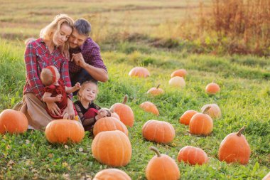 Sonbahar tarlasında turuncu balkabaklı mutlu bir aile. 