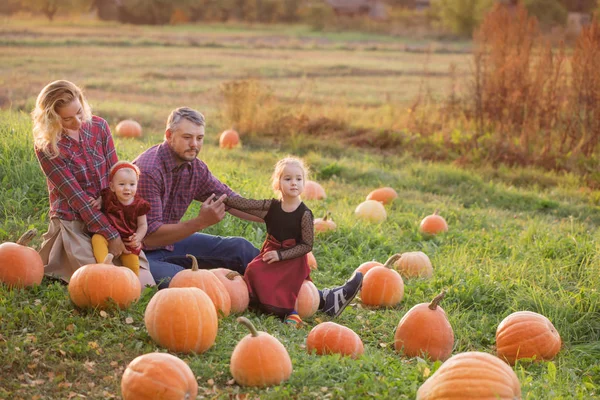 Família feliz com abóboras laranja no campo de outono — Fotografia de Stock
