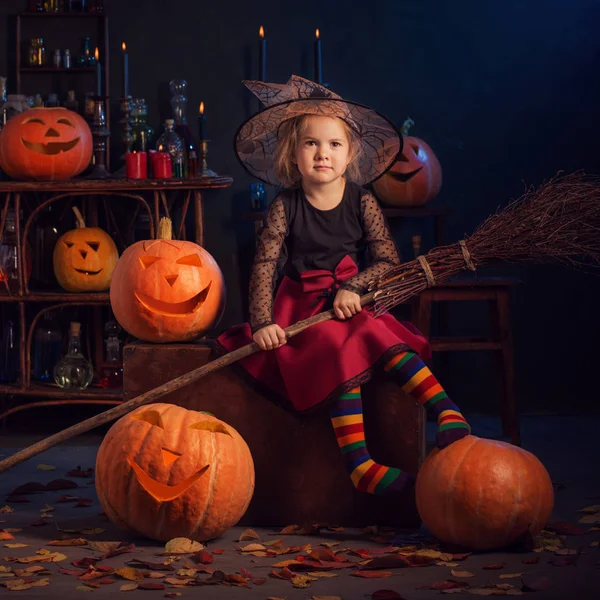 Маленькая ведьма с тыквами в помещении — стоковое фото