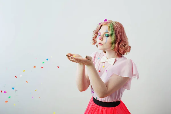 Clown girl blows confetti from hands — Stock Photo, Image
