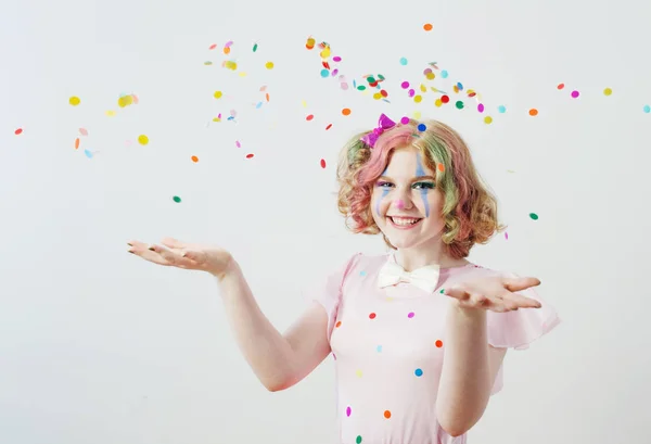 Clown girl blows confetti from hands — Stock Photo, Image