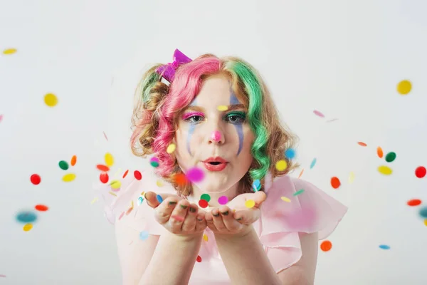Clown girl blows confetti from hands — Stock Photo, Image