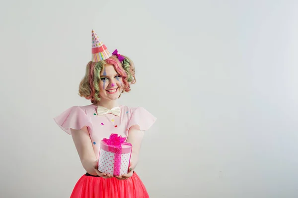 Smile teenager girl in clown costume with box gift on white back — Stock Photo, Image