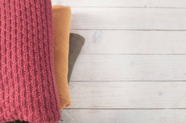 beyaz ahşap masa üzerinde kazak yığını