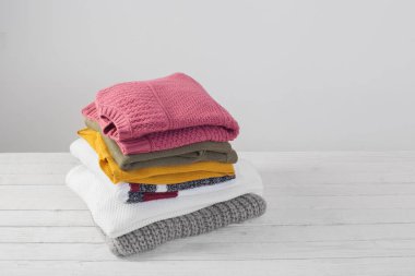 beyaz ahşap masa üzerinde kazak yığını