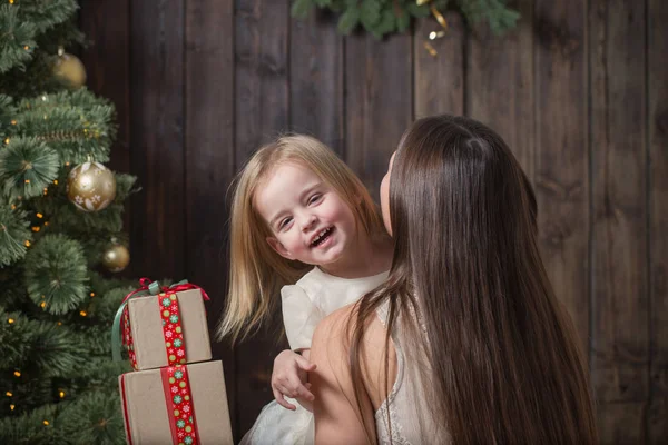 Mãe e filha na árvore de Natal em um fundo de madeira — Fotografia de Stock