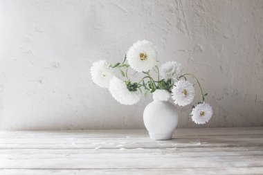beyaz ahşap masa üzerinde vazo içinde asters 