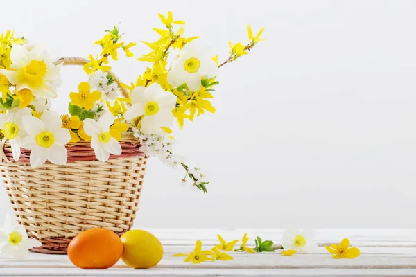Velikonoční vajíčka s jarními květy na bílém dřevěném stole — Stock fotografie