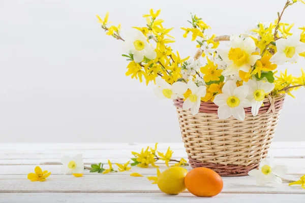 白い木製のテーブルの上に春の花とイースターの卵 — ストック写真