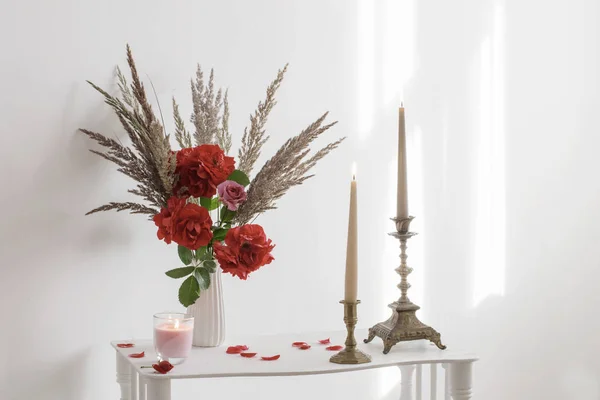 Interior blanco con ramo de rosas y velas encendidas —  Fotos de Stock
