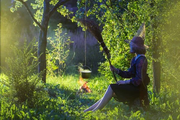 Jovem bruxa pelo fogo na floresta mágica faz em caldeirão panela mágica — Fotografia de Stock