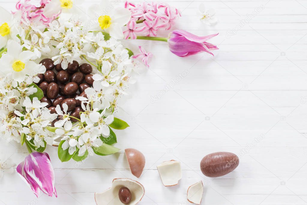 chocolate Easter eggs with spring flowers on wooden background 