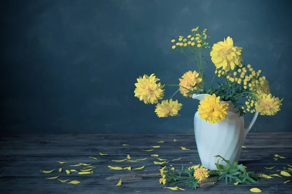 Sárga virágok fehér kancsó kék sötét háttér — Stock Fotó