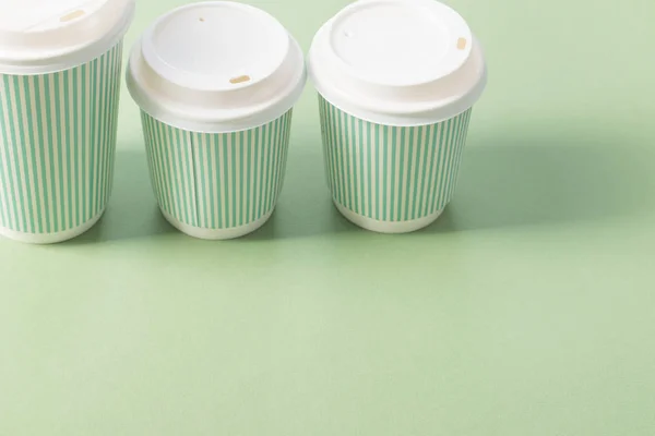 Copo de papel descartável com café no fundo verde — Fotografia de Stock