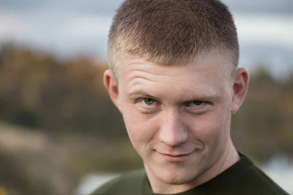 Portret van een jonge man op een achtergrond van een meer in de herfst — Stockfoto