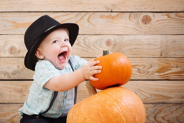 Bambino in cappello nero con zucche su sfondo di legno — Foto Stock