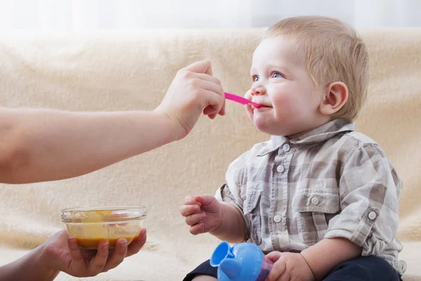 Mutter füttert kleines Kind mit Fruchtpüree — Stockfoto