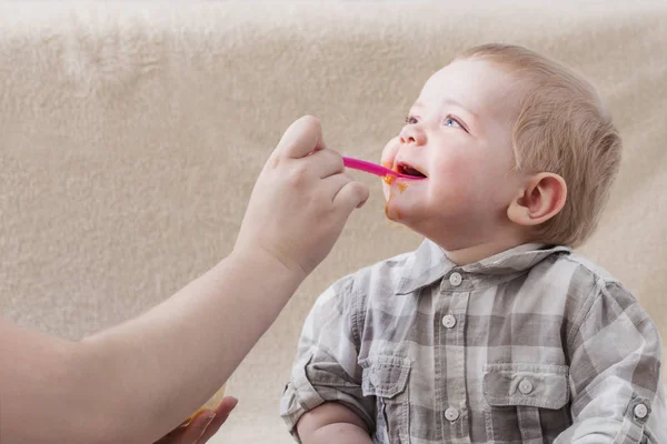 Мати годує маленьку дитину фруктовим пюре — стокове фото