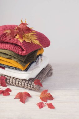 Sonbahar yapraklı kazak yığını beyaz ahşap masada.
