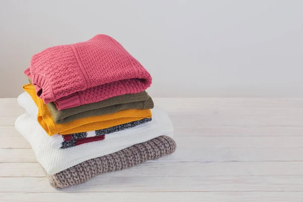 Stos swetry na białym drewnianym stole — Zdjęcie stockowe