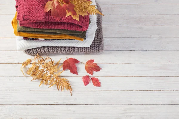 Halom pulóver őszi levelekkel fehér fa asztalon — Stock Fotó