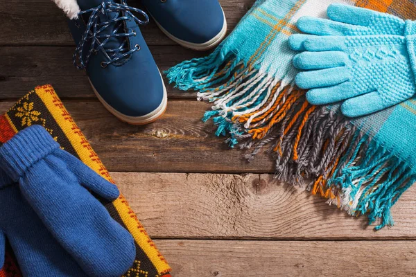 Winter shoes, gloves, scarves  on old wooden background