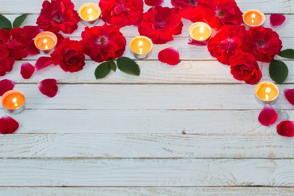 红玫瑰和燃烧的蜡烛在木制白色背景 — 图库照片