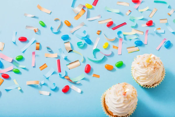 Шляпа на день рождения с конфетти и кексом на фоне голубой бумаги — стоковое фото
