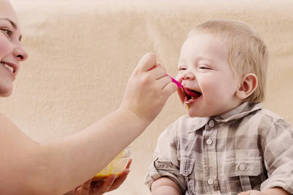 Mutter füttert kleines Kind mit Fruchtpüree — Stockfoto