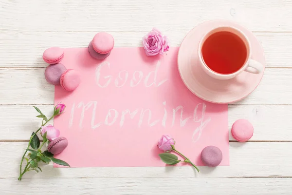 Tazza di tè e amaretti rosa sul tavolo di legno bianco — Foto Stock